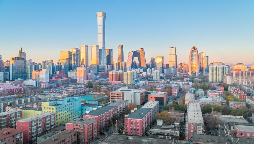 Skyline chinesischer Städte mit Symbolen für Leerstände, fallende Immobilienpreise und wirtschaftliche Unsicherheiten