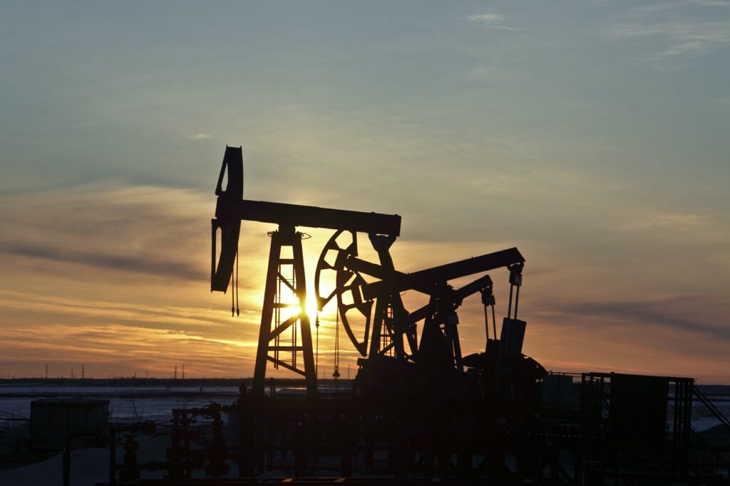 Ein Ölpumpenfeld bei Sonnenuntergang, symbolisierend sinkende Energiepreise und finanzielle Herausforderungen der Ölindustrie.