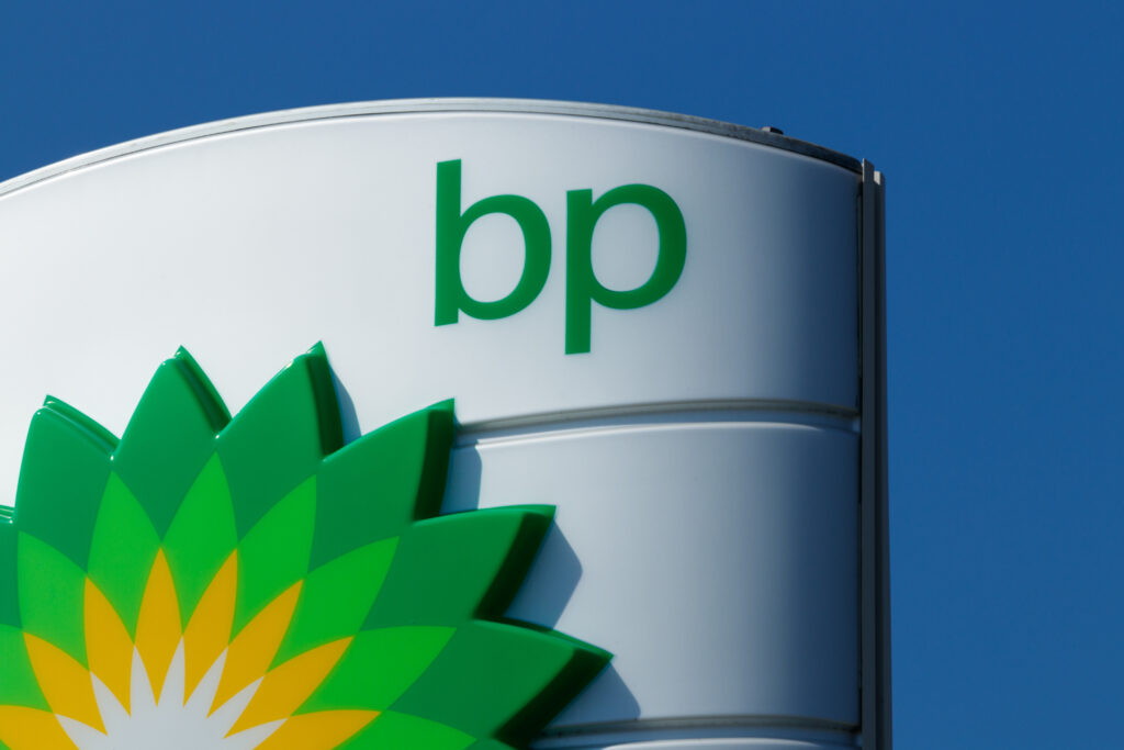 BP unter wirtschaftlichem Druck: BP-Logo vor einem fallenden Börsenkursdiagramm