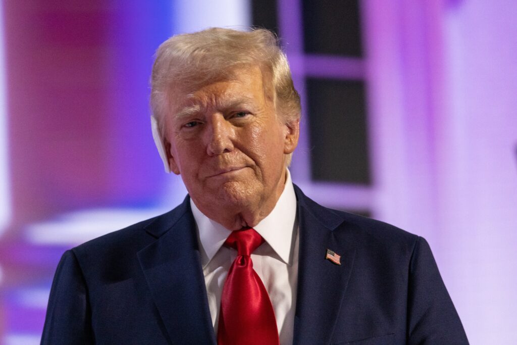 Trump IRS-Pentagon Entlassungen: Donald Trump bei einer Rede, im Hintergrund das IRS- und Pentagon-Gebäude